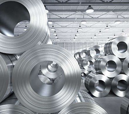 Large rolls of sheet metal stacked on top of each other in a warehouse
