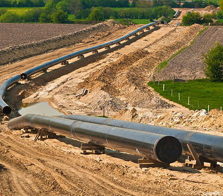 Metal tubing lined up to connect with each other in dug up earth